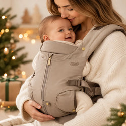 Mãe com bebé no marsúpio Voksi Huddle num ambiente acolhedor com decoração natalícia.